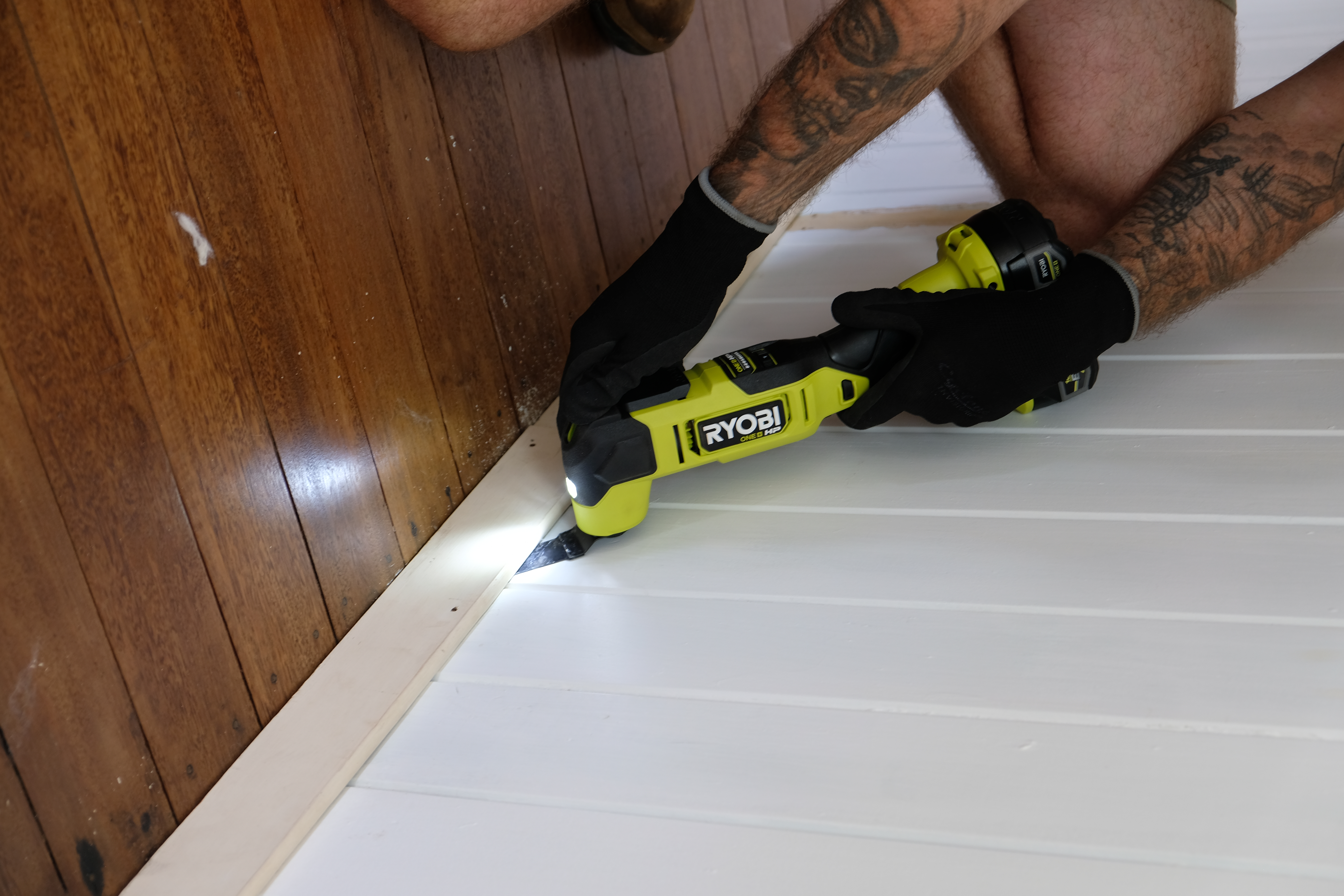 Jake uses a RYOBI multi tool to remove old skirting boards and reside from the wall. 