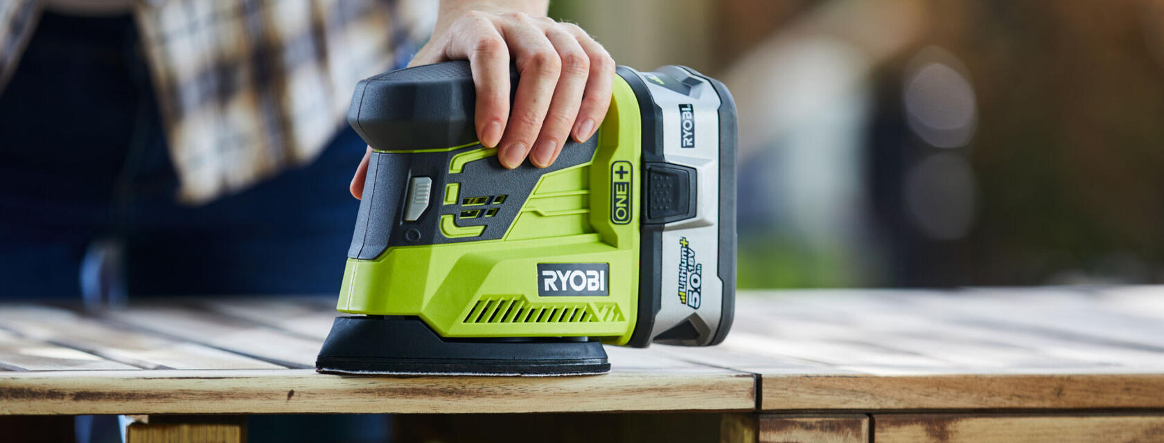 RYOBI sander used on plank of wood held by hand