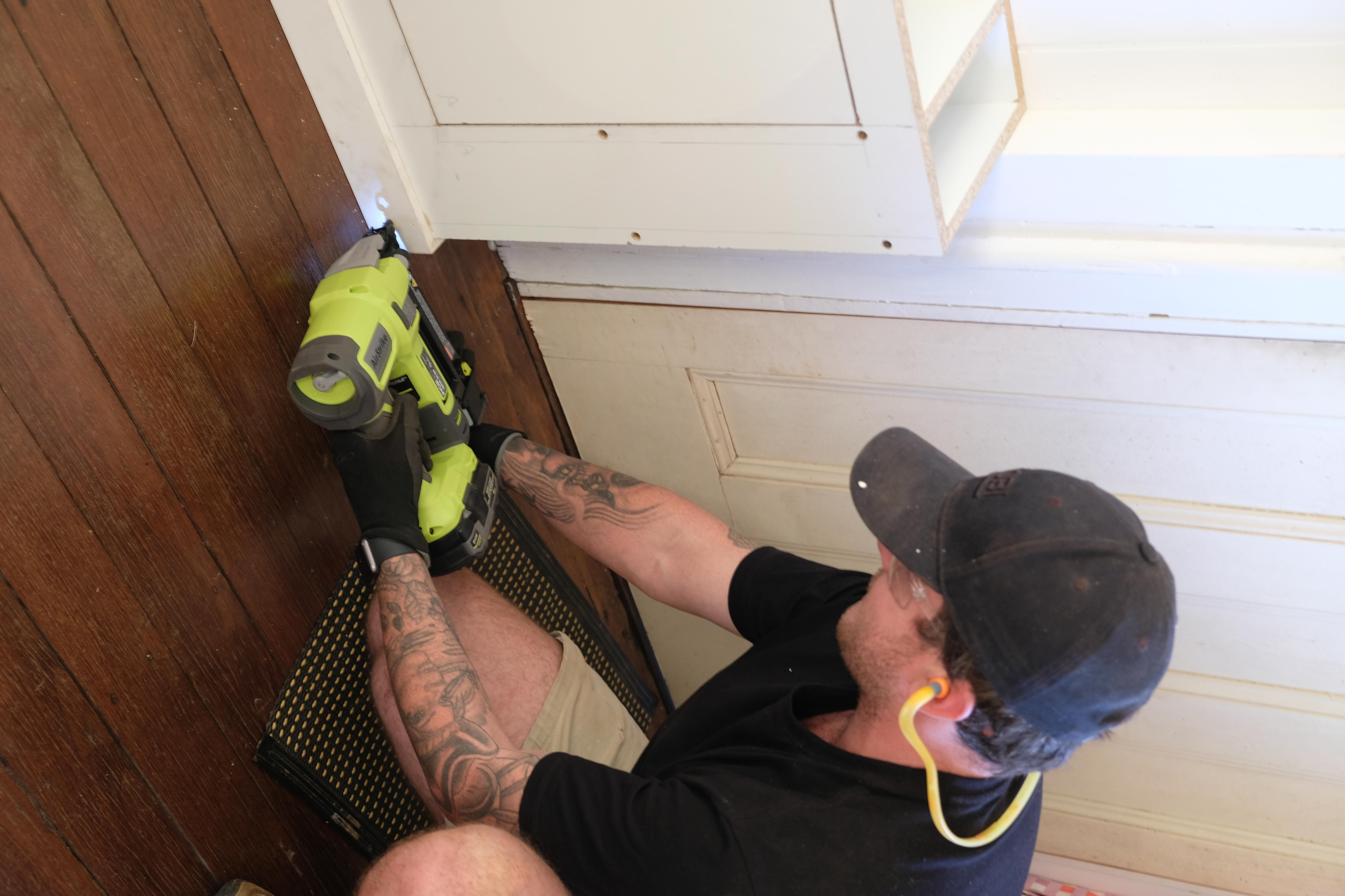 Jake uses a RYOBI brad nailer to secure the decorative pieces to the shoe cabinet. 