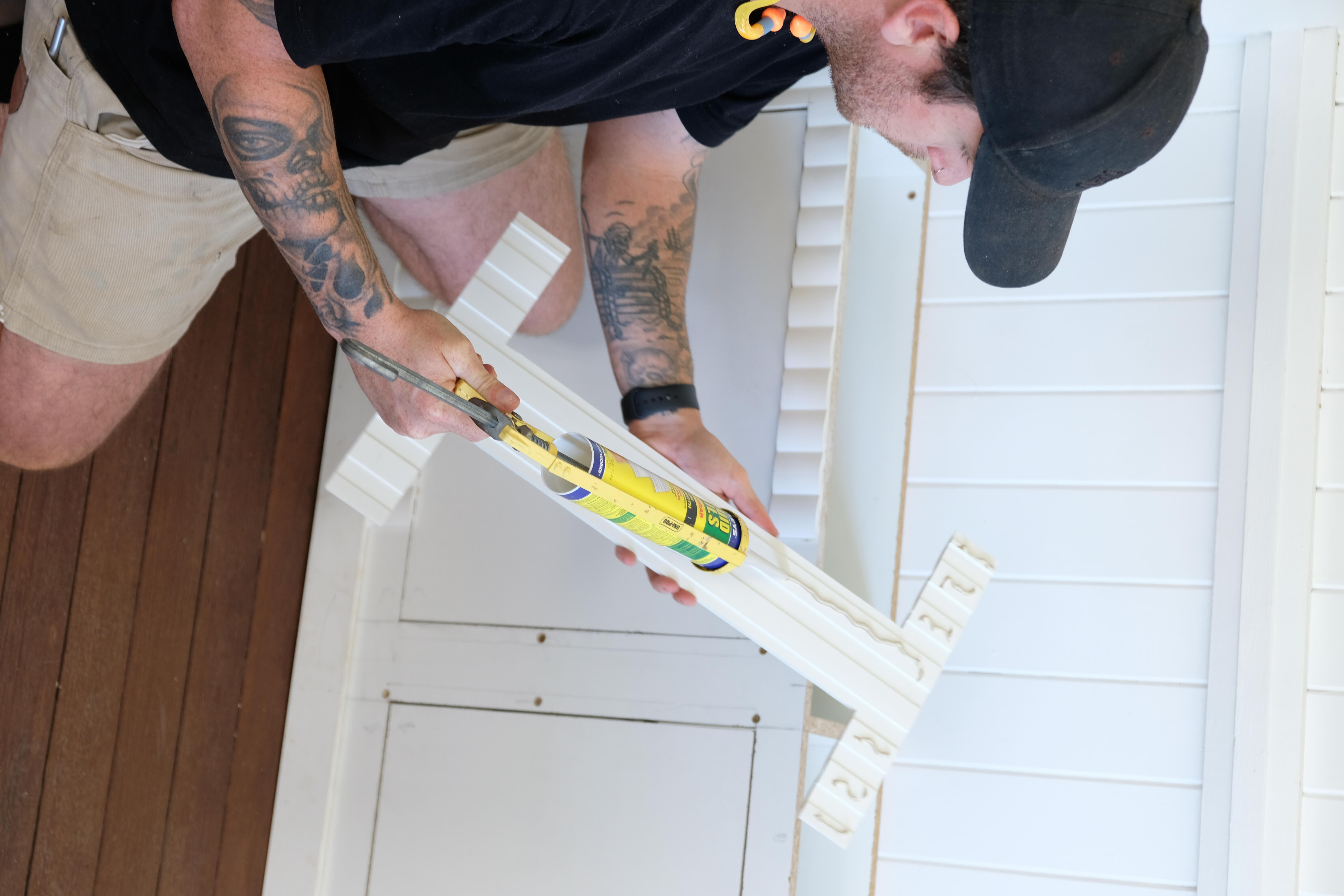 Jake uses silicone adhesive to secure the decorative front pieces to the shoe cabinet. 