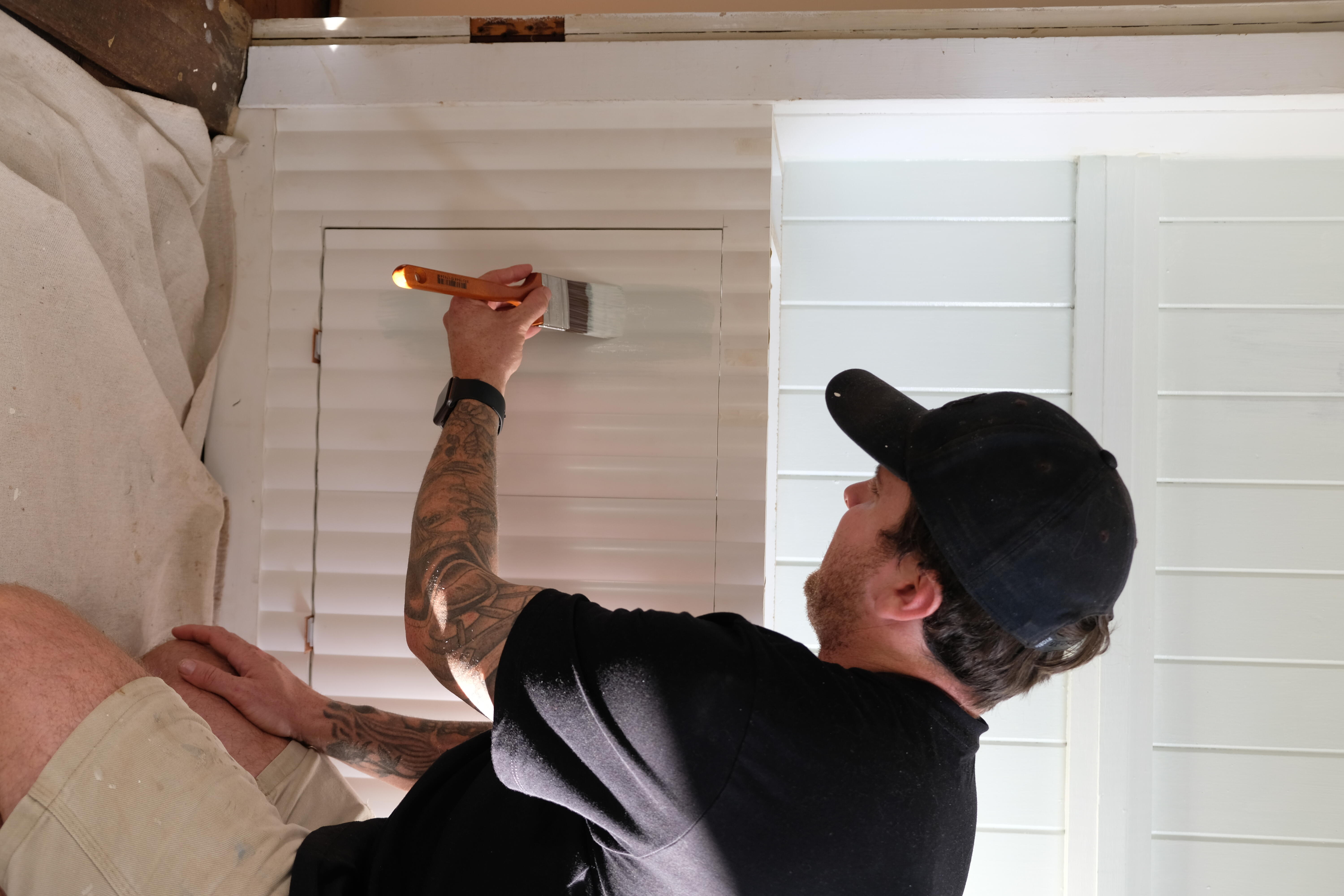 Jake paints the front of the DIY Shoe Cabinet.  