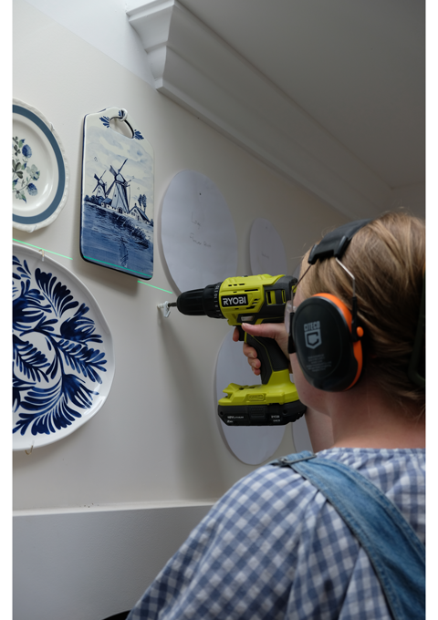 Brooke installs fasteners into the wall using a RYOBI Drill Driver. She is wearing ear and eye protection.