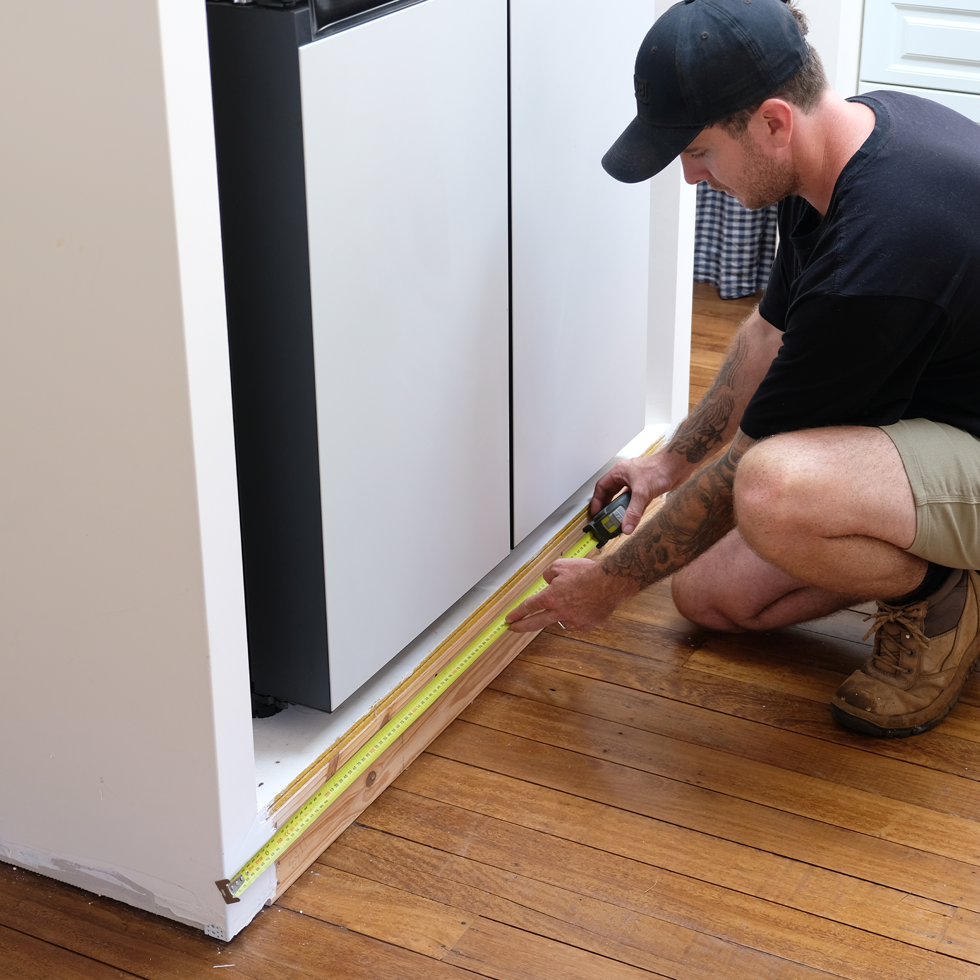 Jake measures the required length of the skirting board using a tape measure. 