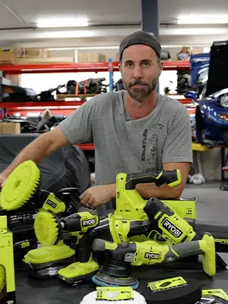 Blair Joscelyne from Mighty Car Mods stands with a pile of RYOBI tools